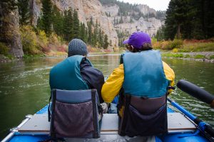 Two people dressed warmly floating in a raft down the Smith River, Montana