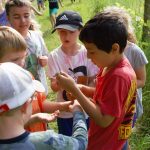 Kids gathered around each other while one holds a garter snake