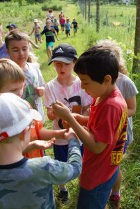 Kids gathered around each other while one holds a garter snake