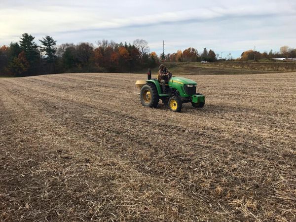 Person driving a John Deere tractor over an empty field